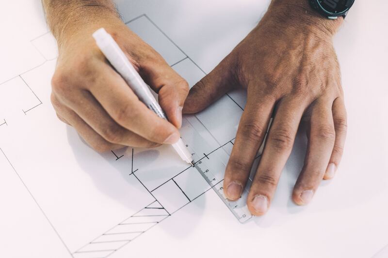 Hands drawing measured lines on paper with a pen and ruler