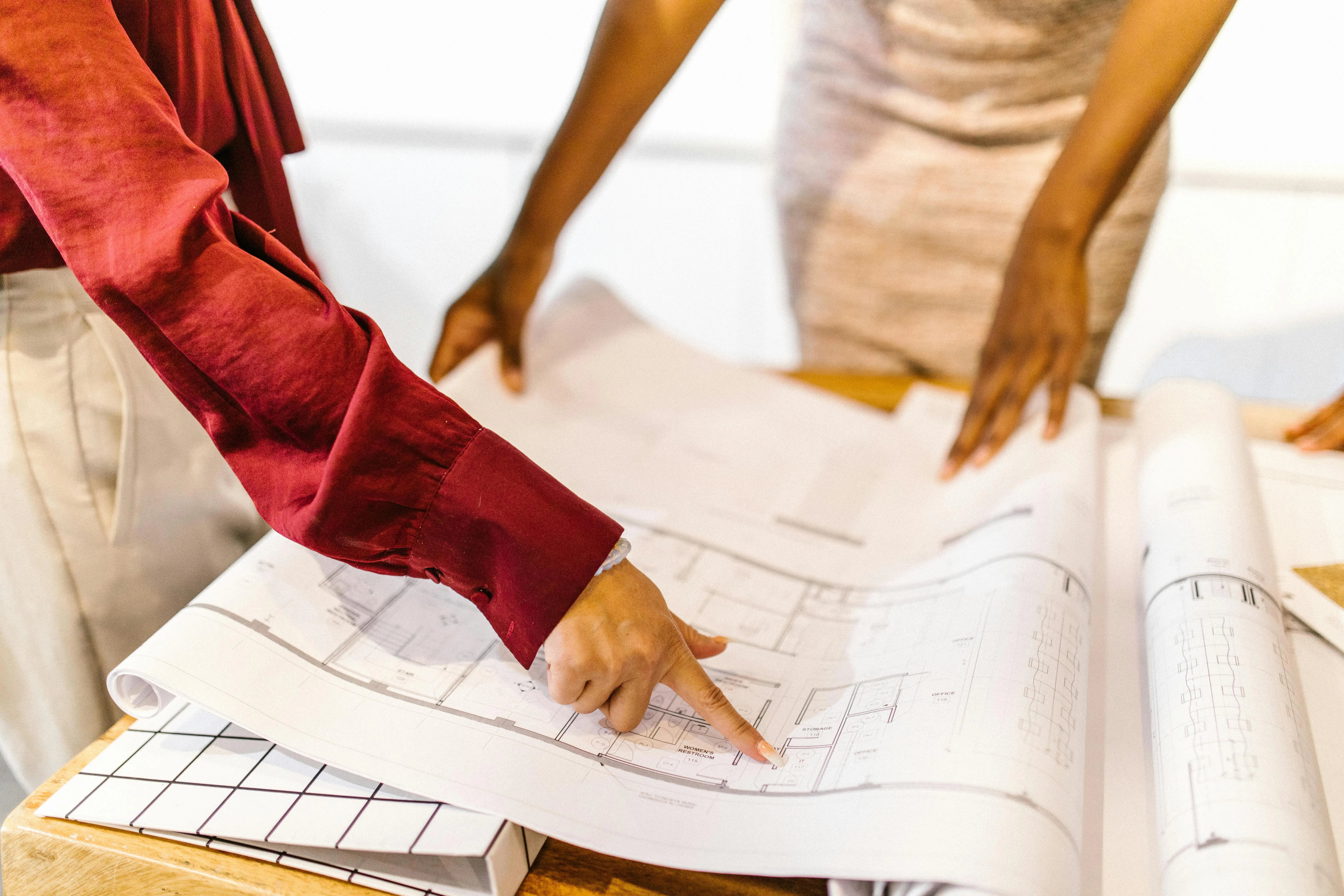 Two people reviewing technical drawings together at a table