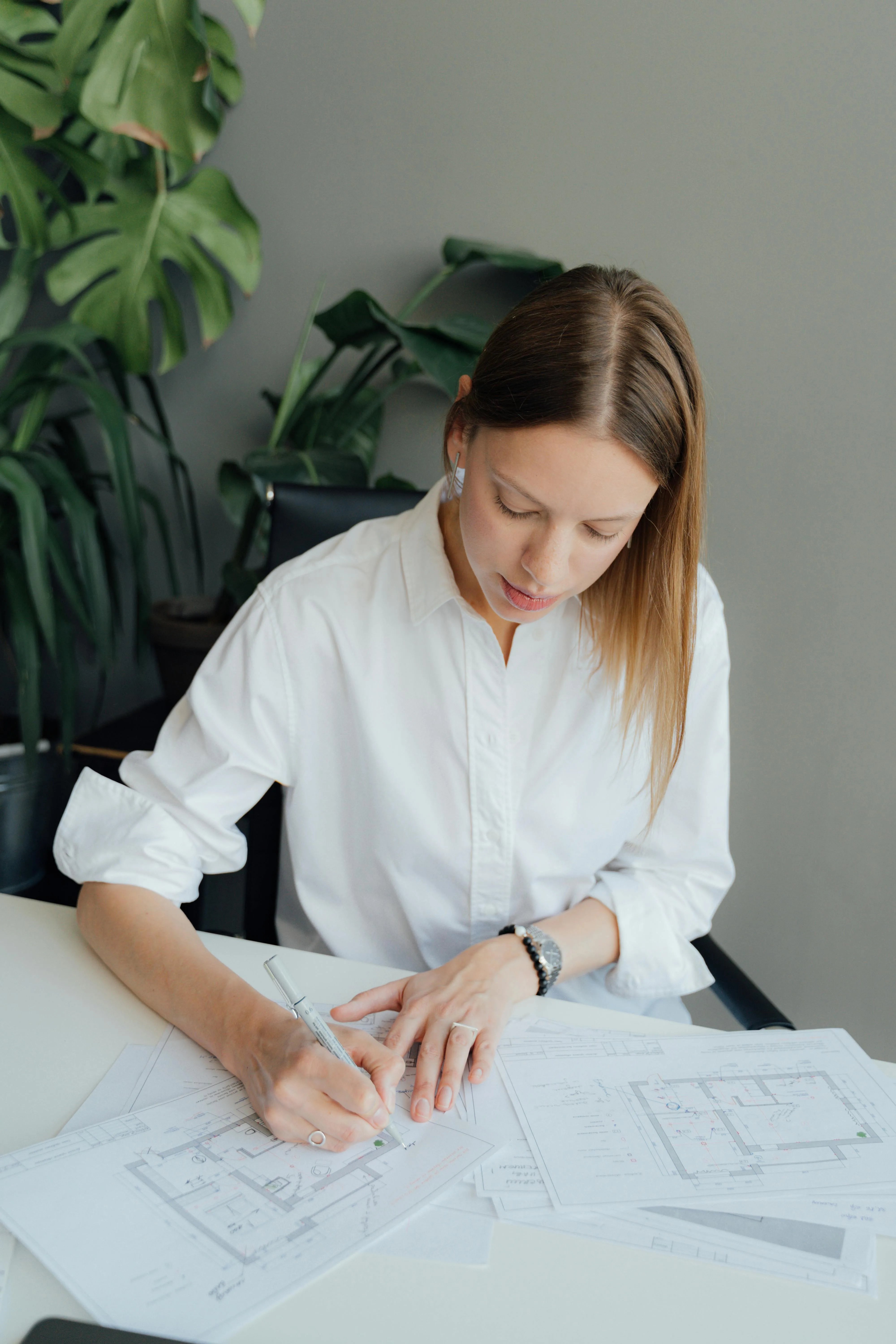 Designer marking up floor plans at a work desk